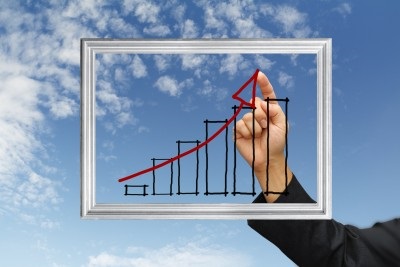photo of man's hand pointing to graph trending upwards, healthcare economics